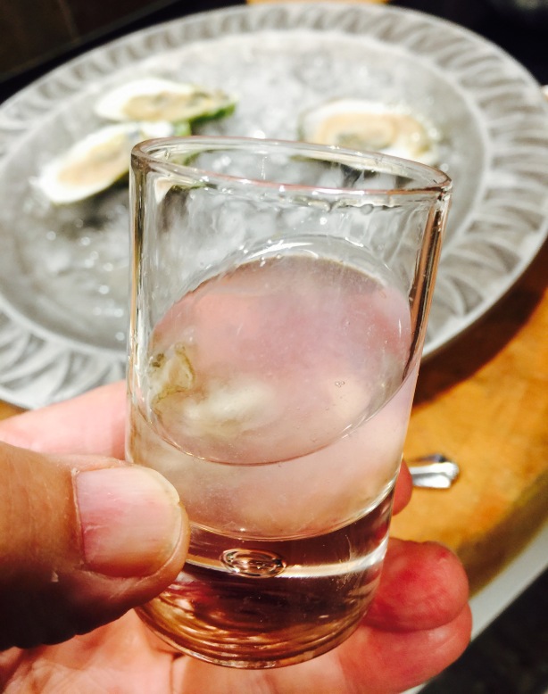An oyster shooter with pickled red onion shaved ice. Bottoms up!